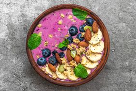 Acai smoothie bowl topped with banana, chia and pumpkin seed, blueberry, almonds and granola. healthy vegan breakfast