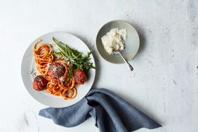 Spaghetti and meatball pasta and parmesan cheese on a table. 