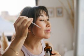 woman applying serum to face with dropper