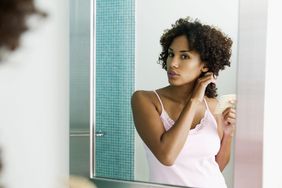 woman combing hair bathroom mirror