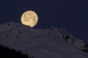 Full moon over snow-capped mountains