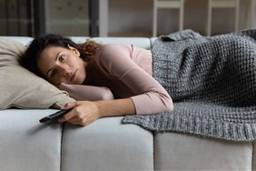 Tired young latin woman watch tv before fall asleep