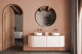 Warm brown bathroom interior with double sink and mirror, carpet on hardwood floor, bathtub, plants. Bathing accessories and window in hotel studio, arches.