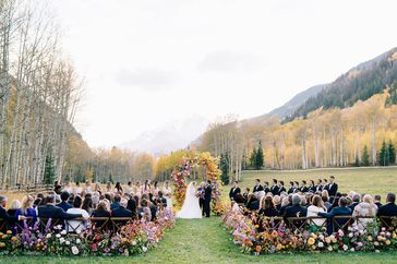 outdoor wedding ceremony with colorful floral archway