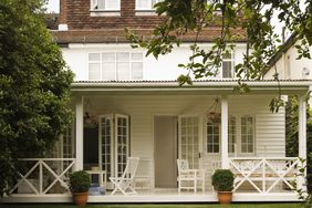 white front porch with potted plants and open door