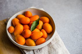 Organic ripe kumquat in the bowl on the concrete table