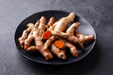 Fresh turmeric, curcumin roots on a black plate