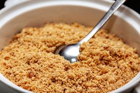 close up view of light brown sugar in white bowl with a spoon 