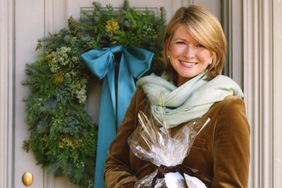 Martha Stewart holding a gift in front of a door with a wreath