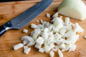 chopped onion with knife on cutting board