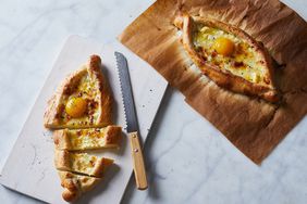 khachapuri sitting on white cutting board with knife