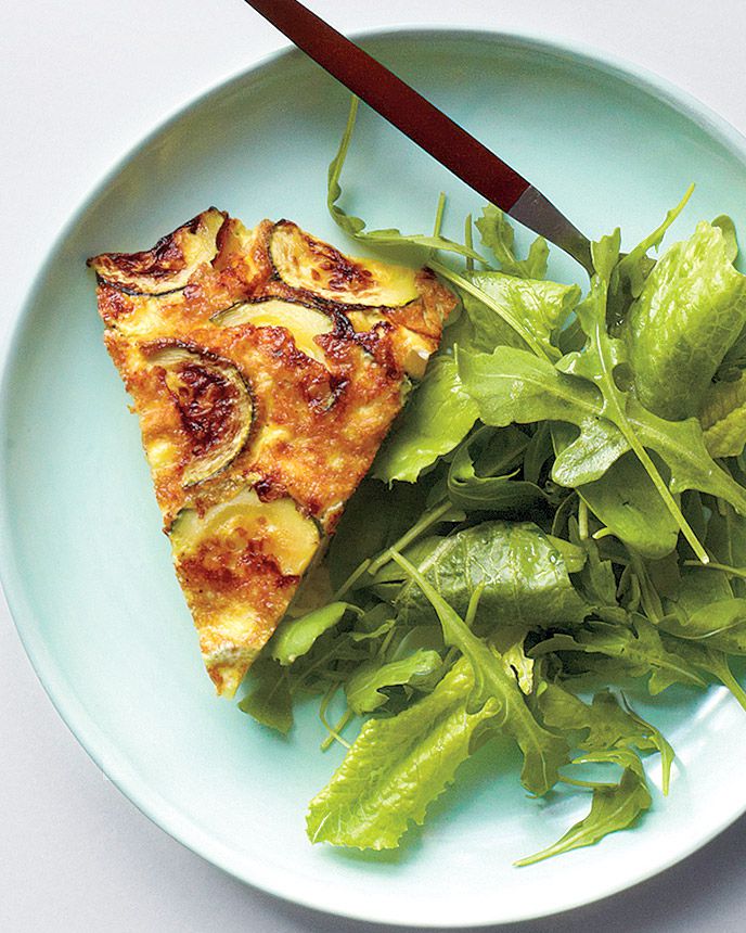 ham, zucchini, and gruyÃ¨re frittata on white plate with salad