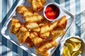 panko breaded fish sticks on a platter with dipping sauce and lemon wedges