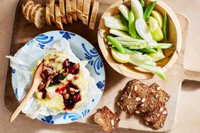 baked cheese with crackers, baguette slices, and crudites on wooden board