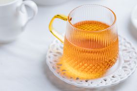 glass mug of chamomile tea on white plate