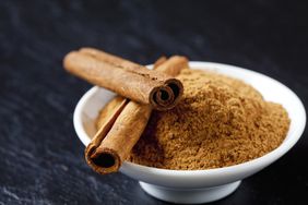 Cinnamon powder in a bowl topped with two cinnamon sticks