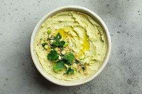 Green dip in bowl with olive oil and greens