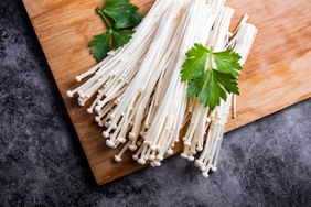 Enoki mushrooms over wooden table background.