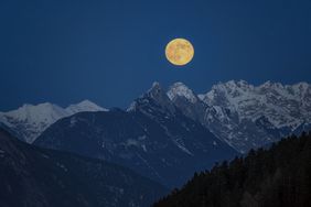 Full moon over snow-capped mountains 