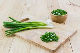 Chopped spring onions on wooden cutting board.