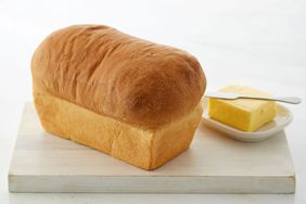 Full loaf of bread on cutting board with butter