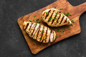 Grilled chicken breast, fillet, steak on wooden board, top view. Healthy keto, ketogenic meal, homemade bbq chicken meat ready to eat.