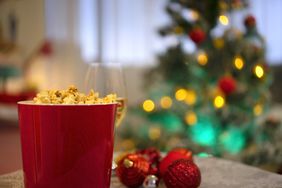 Popcorn and wine on table with Christmas tree in background.