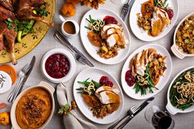 Festive Thankgiving dinner table with plates of food, turkey and all the sides