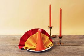 folded turkey napkins with two candles on table