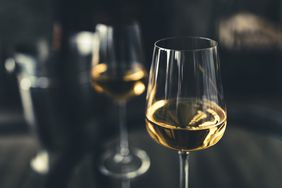 two glasses of white wine with ice bucket in background