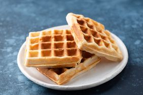 Belgian waffles on a plate, blue background. Sweet breakfast waffles