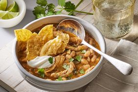 bowl of white chicken chili with spoon and tortilla chips, limes