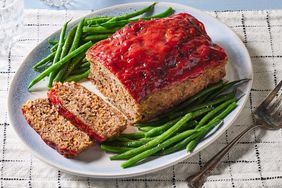 platter of meatloaf with a few slices cut and green beans