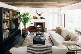 neutral family room with velvet chair and antlers hanging above fireplace