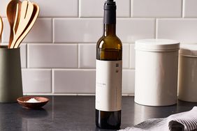 bottle of olive oil on a black countertop with white backsplash