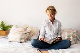 woman reading on bed in outside clothes