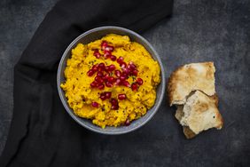 Pita bread and bowl of pumpkin hummus with black sesame and pomegranate seeds