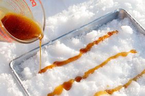 making maple taffy by pouring syrup on snow