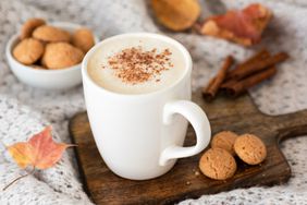 Pumpkin spice latte or cappucino and cookies on wooden serving tray. Autumn comfort food, warm coffee with milk foam in white cup