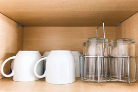 Close-up of cups and glasses neatly arranged facing down in kitchen cabinet