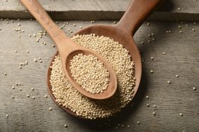 bowl of uncooked sorghum with wooden spoon