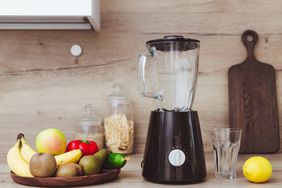 Stationary blender and ingredients for healthy smoothie on table in kitchen.