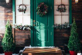 Porch with wooden doors and a threshold with Christmas decor.