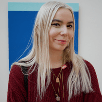 A blonde woman in front of a blue painting